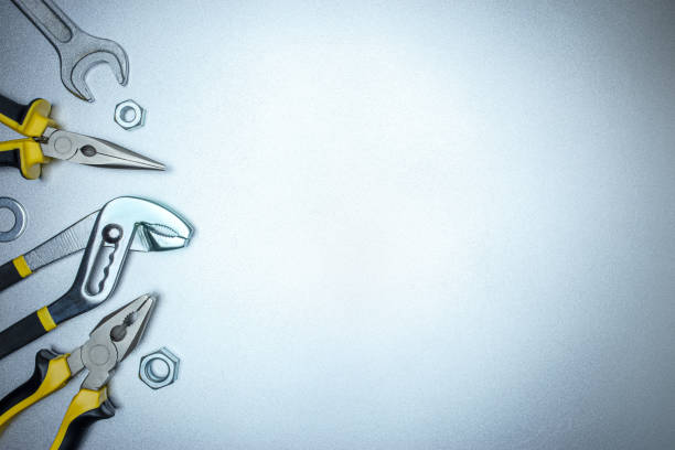 set of different pliers on grey metal background, top view. hand tools for house renovation