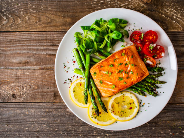 istock Fried salmon steak and asparagus on wooden table 1247005486