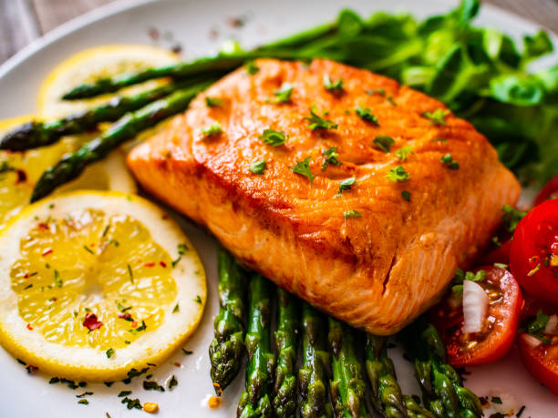 istock Fried salmon steak and asparagus on wooden table 1247005511