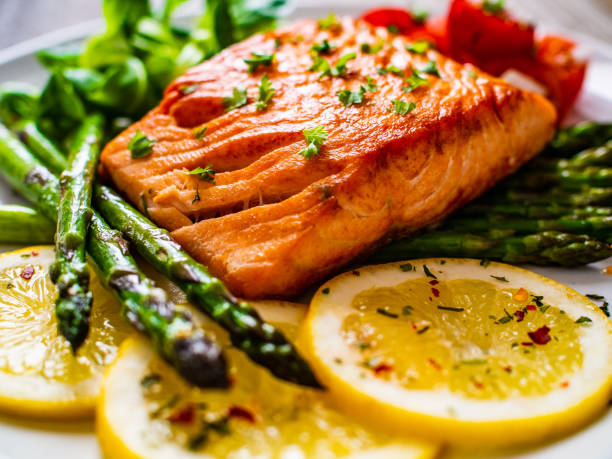 istock Fried salmon steak and asparagus on wooden table 1247005577