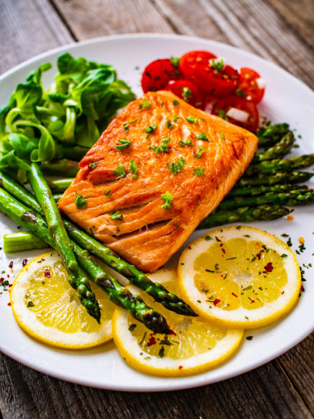 istock Fried salmon steak and asparagus on wooden table 1247005618