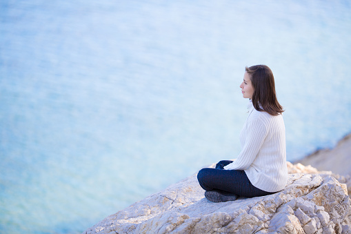 young attractive woman sitting on the beach and looks pensive on the sea