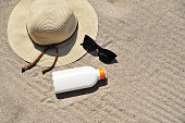 Hat and sun cream protection on sand. Summer time concept.