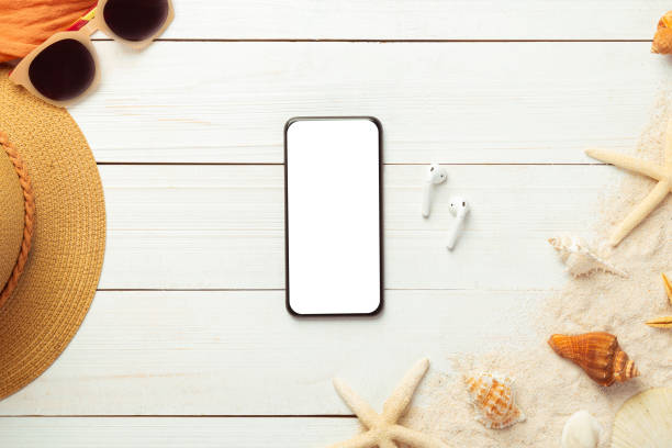 istock Summer background with blank screen phone and beach accessories - straw hat, sunglasses on white wood table background top view with copy space 1247016736