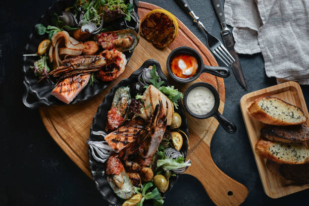 istock Fresh seafood on a stone table. Oysters, prawns and scallops, squids, served by the chef, beautifully laid out on plates, dark concrete background. View from above 1247018948