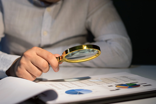 Businessman examines the budget with  magnifying glass