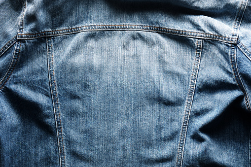 Back side of a vintage blue jeans or denim jacket with copy space. Close up view.