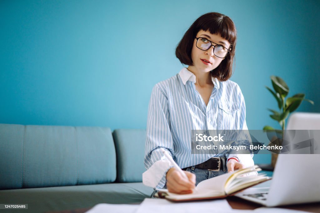 Beautiful woman at home writing and working with diary. Beautiful woman at home writing and working with diary. Freelance and remote work concept. Author Stock Photo