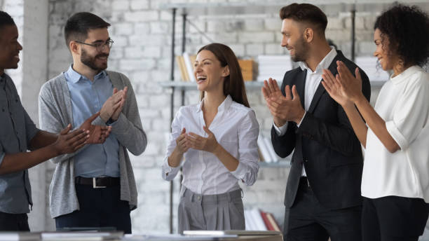 Friendly diverse employees congratulating businesswoman with business achievement Friendly diverse employees congratulating businesswoman with business achievement, great work results or job promotion, business people applauding and cheering, standing in modern office cheering photos stock pictures, royalty-free photos & images