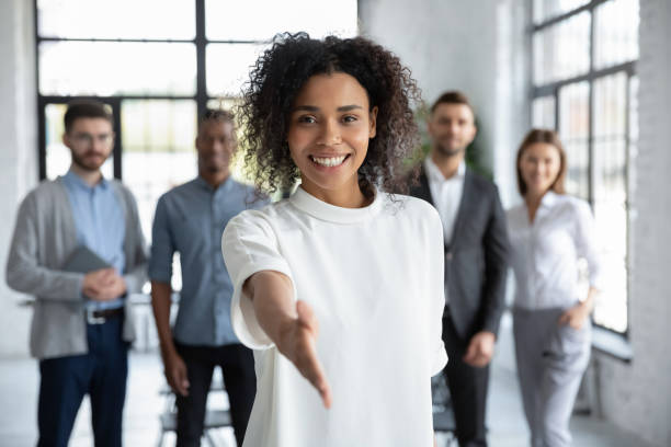 Head shot portrait smiling African American businesswoman offering handshake Head shot portrait smiling African American businesswoman offering handshake, standing with extended hand in modern office, friendly hr manager or team leader greeting or welcoming new worker greeting stock pictures, royalty-free photos & images