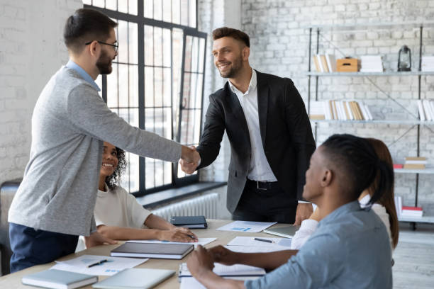 istock Smiling business partners shaking hands at group negotiations 1247026318