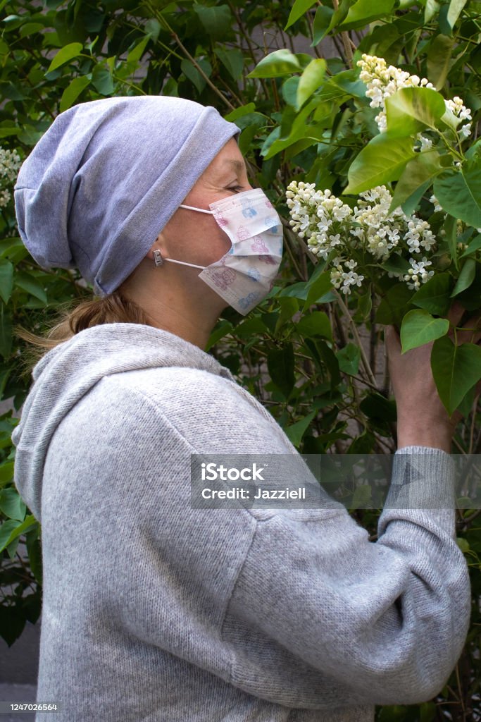 женщина в медицинской маске лица пахнущие белой сиренью - Стоковые фото Covid-19 роялти-фри