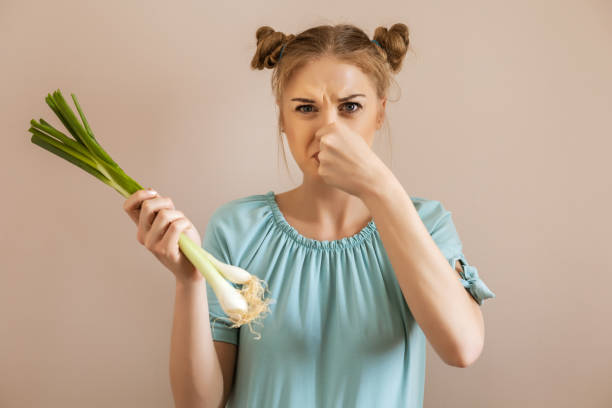 Unpleasant smell of onion Cute woman doesn't like the smell of onion. holding nose stock pictures, royalty-free photos & images