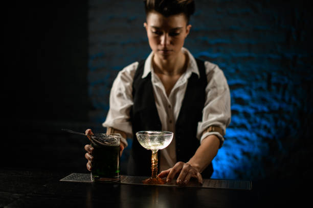 las manos del barman en el vidrio y la taza de mezcla con el puesto de cóctel frío verde en el mostrador del bar - combinaciones de traje negro fotografías e imágenes de stock