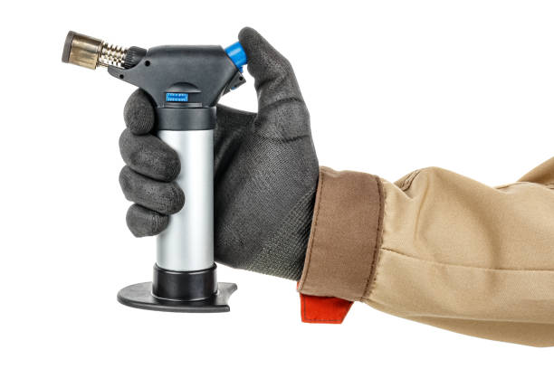 istock Man hand in black protective glove and brown uniform holding small butane torch isolated on white background 1247029162
