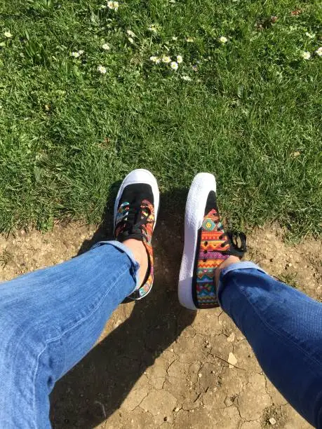 Photo of Male human legs wearing jeans and skate shoes, with bare ankles.