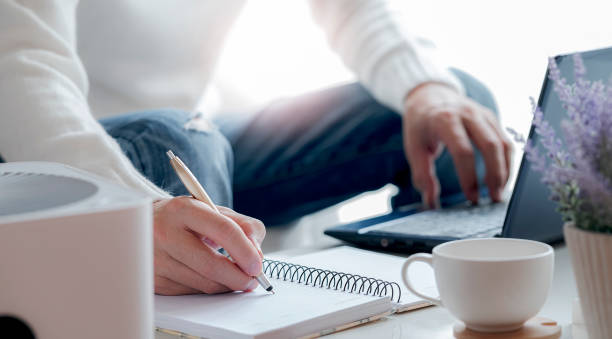 istock Side view of man hand writing on notebook with pen while working at home. 1247039530