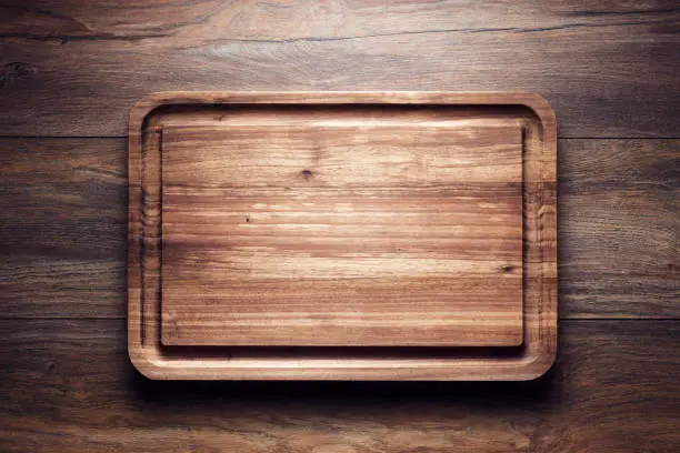 Empty vintage wooden cutting board on wooden table. Overhead view with copy space.