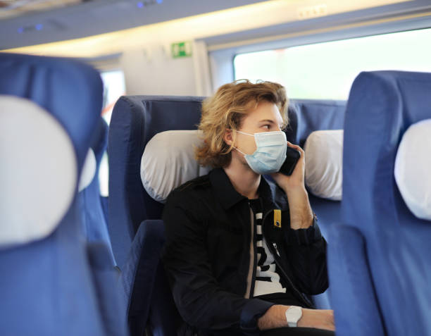 istock Young  man wearing  surgical face mask waiting for the train,using smartphone, typing a message on the phone. 1247050091