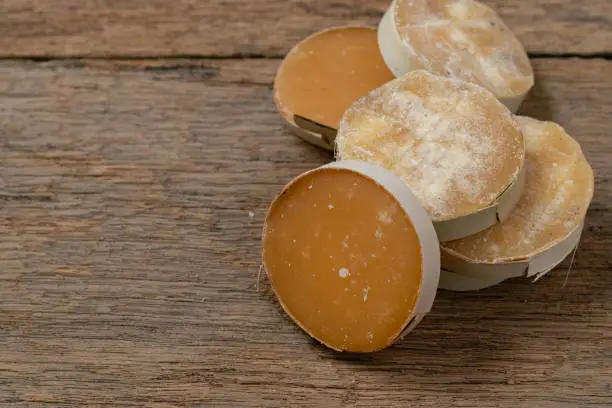 Photo of Jaggery on palm sugar on wooden table.