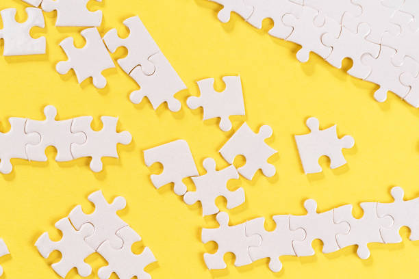 istock White jigsaw puzzle pieces on yellow background 1247055283