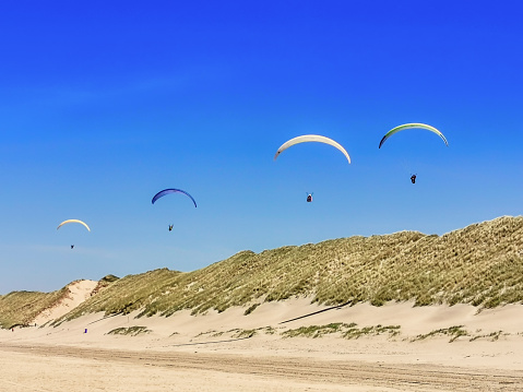 Para glider flying above the dunes en beach having fun and a great adventure.
