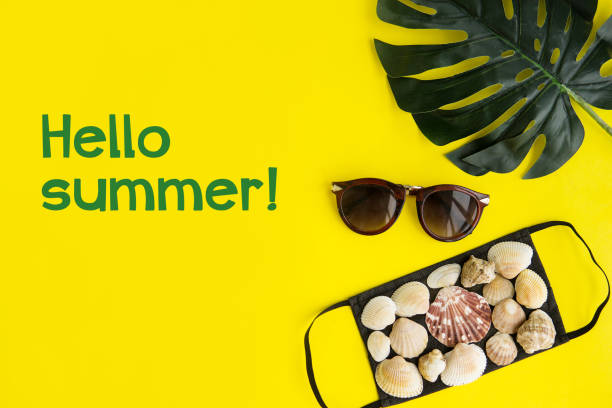 istock Black medical face mask and seashells, sunglasses, monstera leaf on a yellow background. Flat lying, copy space, vacation cancellation, pandemic, tourism. 1247063864