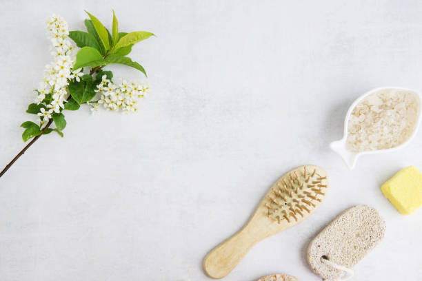 Concept of Spa-cosmetic and cosmetic procedures. Spa-sea salt in a white dish, wooden comb, penza, flower on a light concrete background. The concept of a waste-free lifestyle. copyspase. stock photo