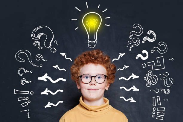 istock Happy kid student with lightbulb on blackboard background. Brainstorming and idea concept 1247081535