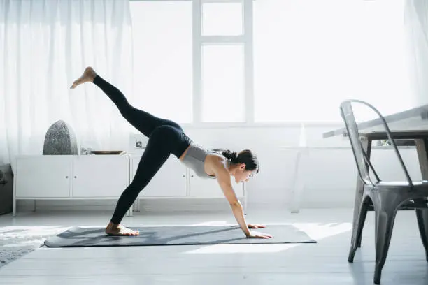 Photo of Young Asian woman practicing yoga in the living room at home in the morning