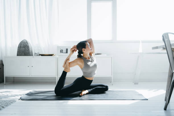 joven asiática practicando yoga en la sala de estar en casa por la mañana - stretching yoga zen like beauty fotografías e imágenes de stock