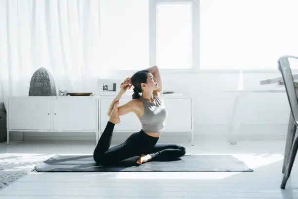 Young Asian woman practicing yoga in the living room at home in the morning Young Asian woman practicing yoga in the living room at home in the morning
