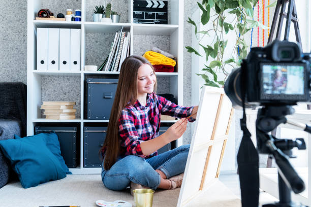istock Woman making a video for her blog on art using a tripod mounted digital camera 1247094073