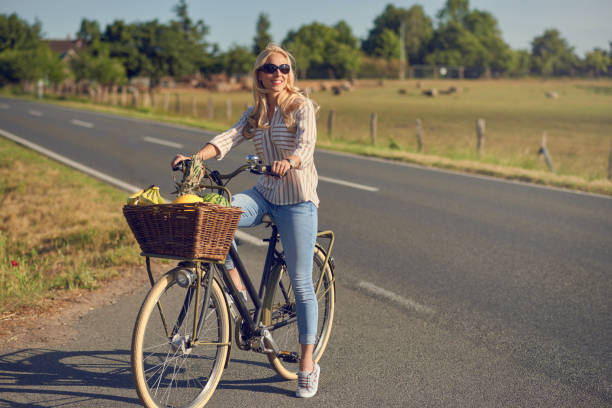 mittelalte blonde frau einkaufen für lebensmittel auf ihrem fahrrad - fahrradkorb stock-fotos und bilder