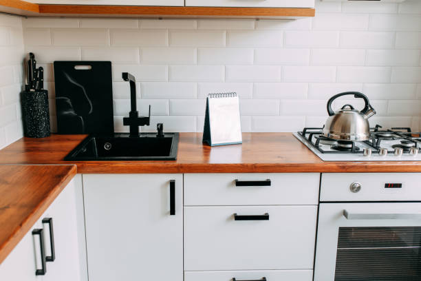 istock Black faucet and sink. Bright kitchen interior. White modern dining room. Wooden complete kitchen with gas oven 1247171447