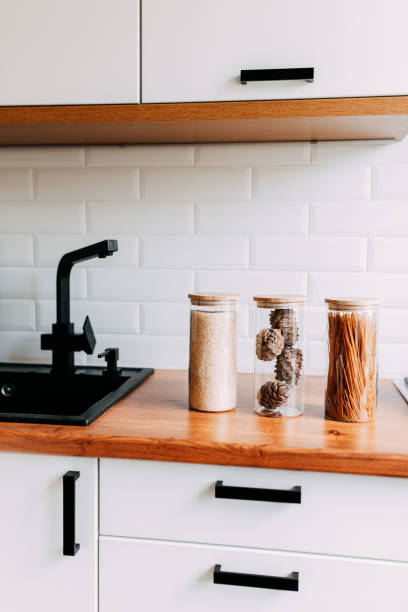 istock Glass jars with grain in kitchen. Bright kitchen interior. White modern dining room. Wooden complete kitchen with gas oven 1247171520