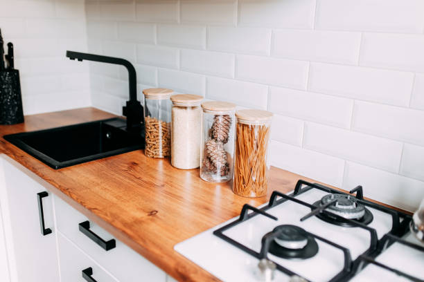 istock Glass jars with grain in kitchen. Bright kitchen interior. White modern dining room. Wooden complete kitchen with gas oven 1247171523