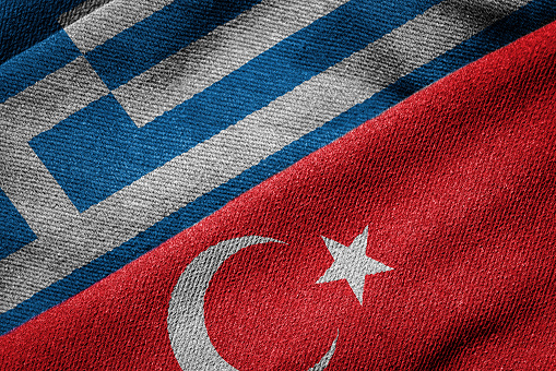 3D rendering of the flags of Greece and Turkey woven fabric texture. Detailed textile pattern and grunge theme. Concept of relations between the two countries marked by alternating periods of mutual hostility and reconciliation.