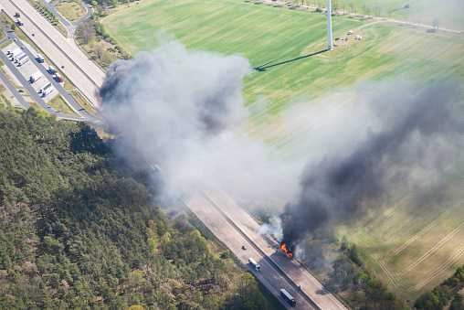Fire on highway - strong black smoke rises to the sky, flames are visible - two trucks caught fire on a highway and burn out completely - aerial view