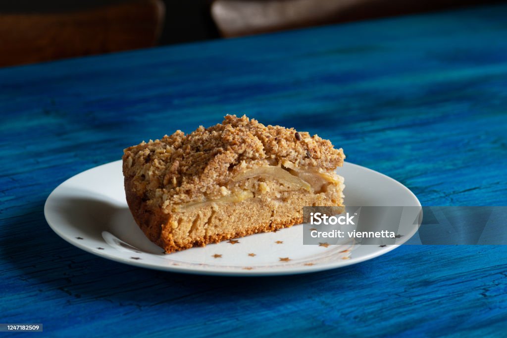 Slice of Irish Apple Cinnamon Streusel Coffee Cake on Star Plate on Blue Table A single slice of Irish apple cinnamon coffee cake with a streusel topping on a white plate with golden stars. The piece of cake is on a blue table. Apple - Fruit Stock Photo