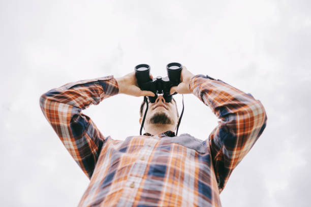 istock Bottom view of traveler young man watching with binoculars. 1247185028