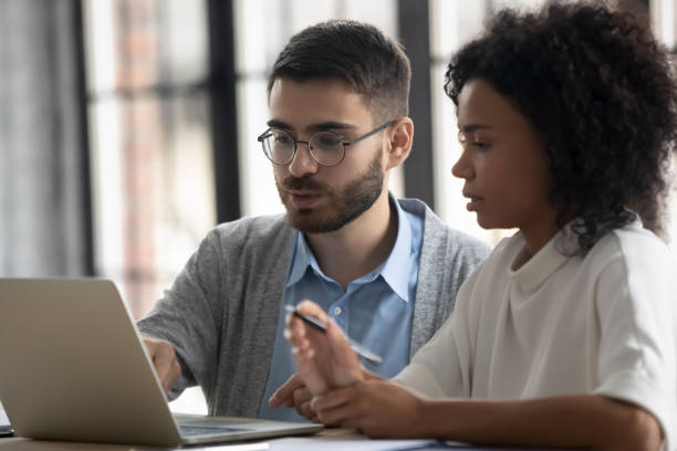 istock Confident mentor teaching African American businesswoman, helping with software 1247195234
