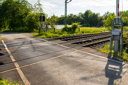 Empty railroad crossing in the countryside, on the road with open barriers.