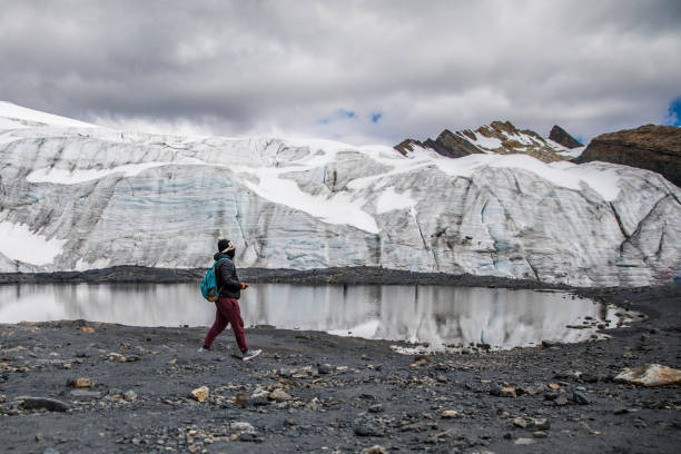 istock man walking in a glacier, little lake and cloudy 1247230863