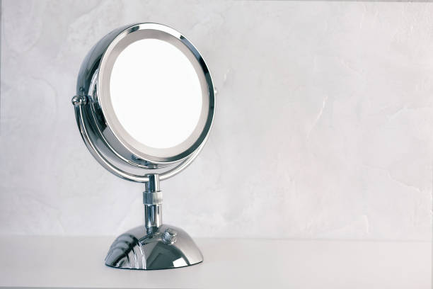 istock Chromed steel round magnifying mirror on handle set up on the table. Cold light background, the atmosphere of purity and cleanliness. 1247244781