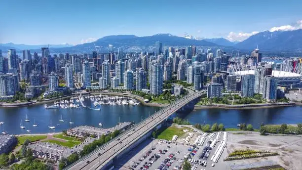 A sunny mid 2020 aerial shot of downtown Vancouver, Yaletown, a marina, North Shore mountains, BC Place, False Creek and the Cambie bridge.