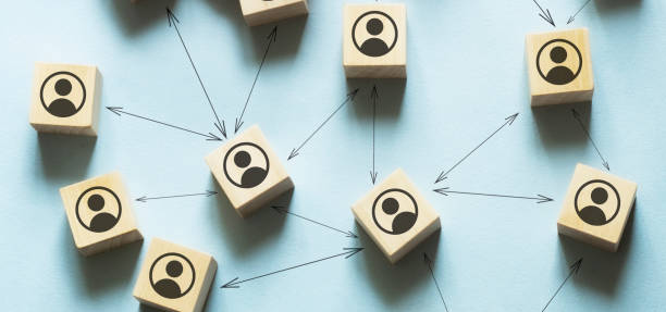 Conceptual image of network marketing - male hand connecting the wooden cut circles with person icon on them. stock photo