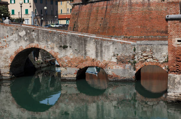 Old brick bridge with three arches reflecting in the water of the river