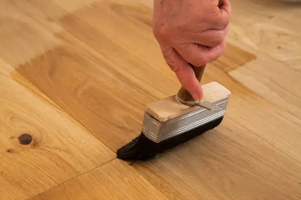 Application  of oil-based floor finish on luxury oak parquet flooring, which tends to enhance the appearance of parquet
