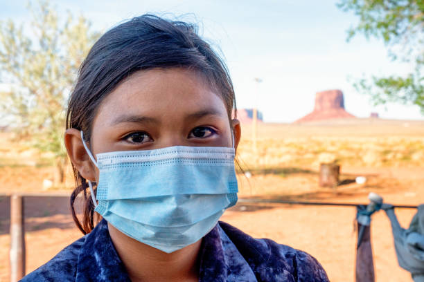Young Navajo Girl in Monument Valley posing with a mask in front of the rock landmarks in the area wearing a Covid-19 Corona Virus Mask Young Navajo Girl in Monument Valley posing with a mask in front of the rock landmarks in the area wearing a Covid-19 Corona Virus Mask navajo nation covid stock pictures, royalty-free photos & images